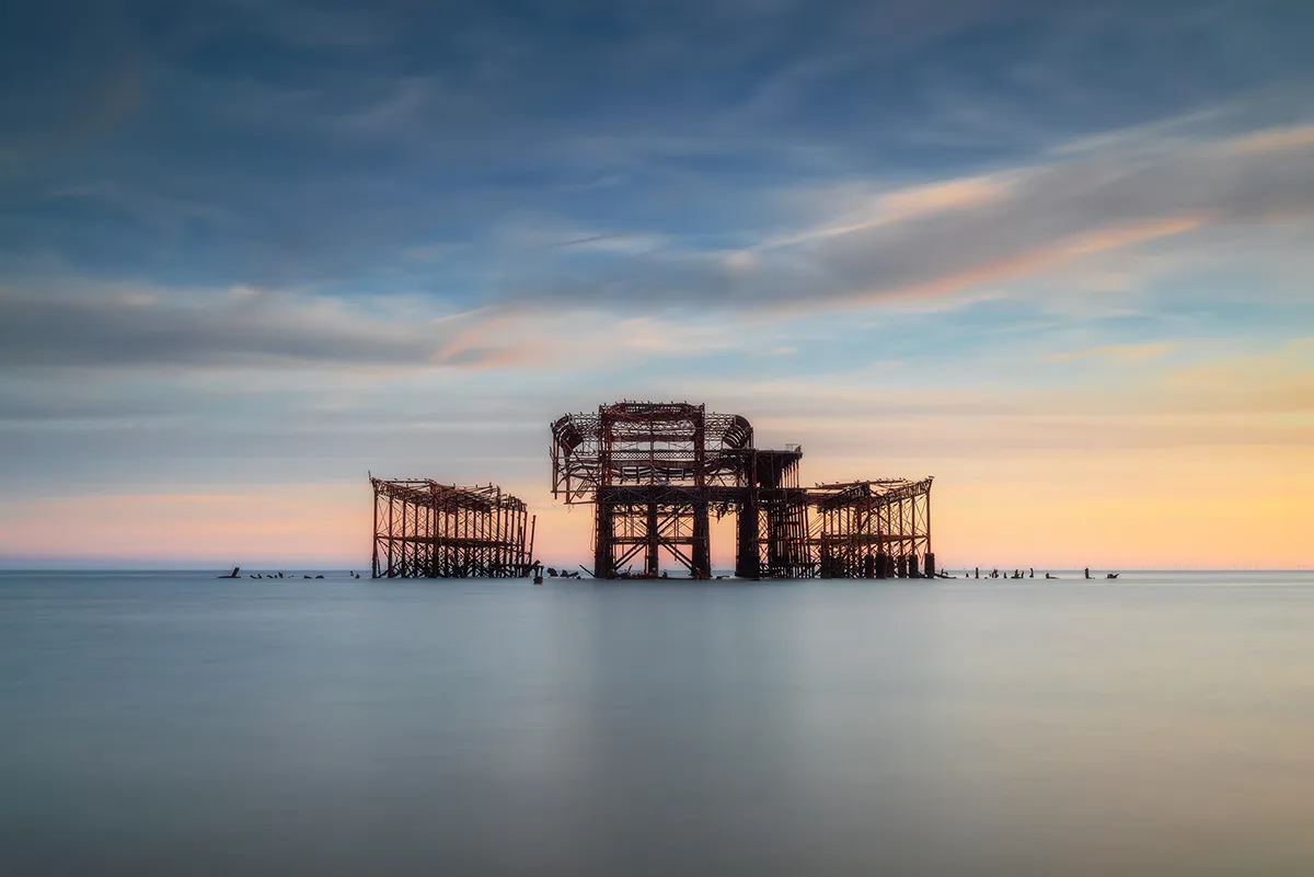 The skeletal remains of the West Pier standing in calm long-exposure water at Brighton