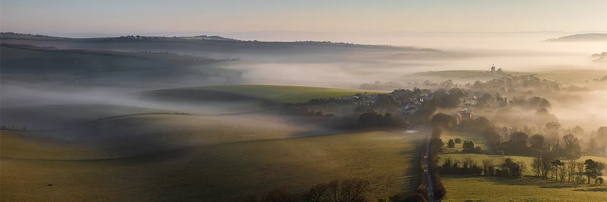 Rolling South Downs hills with low mist drifting through Kingston village in East Sussex at sunrise
